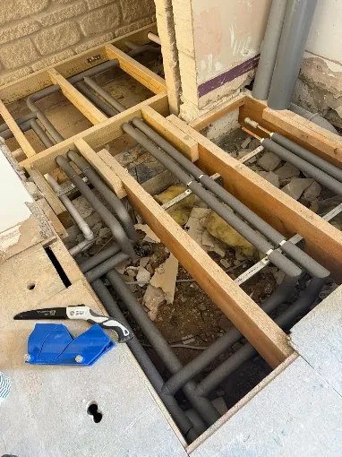 Insulated heating pipework run between floor joists