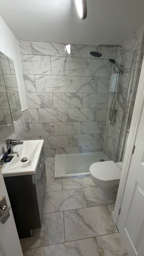 Compact bathroom with walk-in shower and marble-effect tiles